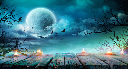 Fototapeta premium Halloween Background - Old Table With Candles And Branches At Spooky Night With Full Moon 