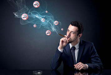 Businessman smoking with floating no smoking signs beside his head.