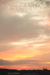 Evening sky after sunset with red clouds and the silhouette of the private sector of a small town