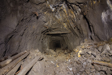 Underground abandoned gold iron ore mine shaft tunnel gallery passage with timbering wooden