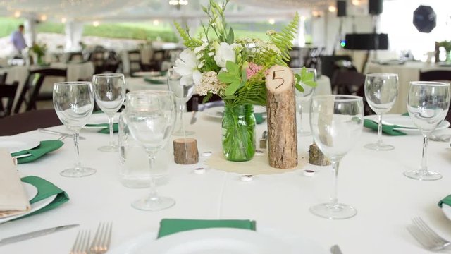 A Rustic Wedding Reception Dinner Table Setup Inside of a Large Outdoor Tent, Slider Shot