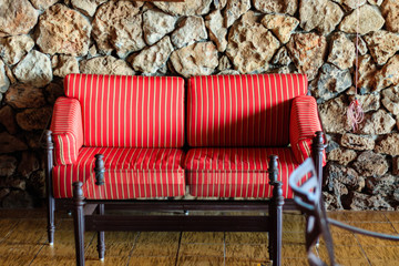 Red couch and glass table in front of a stone wall.