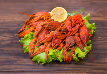 a large plate of boiled red crawfish with lemon and greens on a wooden background