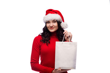 brunette woman wearing christmas hat holding present with a happy face. Isolated over white background