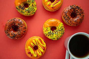 Halloween and Autumn colored tasty colorful donuts served for breakfast on a kitchen table with piping hot coffee.
