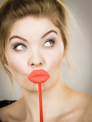 Funny woman holding big red lips on stick