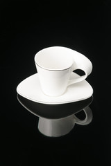 Coffee tea porcelain clay cup with saucer on the black mirror background. Copy space.  .