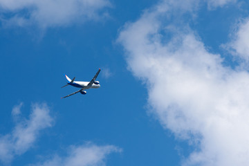 Fototapeta na wymiar Passenger airplane gain altitude against blue sky and white clouds.