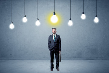 Fototapeta premium Handsome businessman in an empty space with bulbs above and uninspired face 