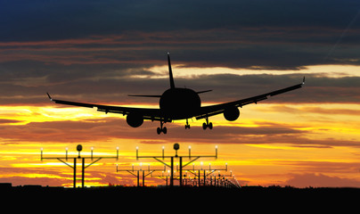 Airplane landing on sunset sky