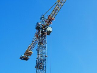 Fototapeta na wymiar Huge industrial crane against blue sky. Construction site.