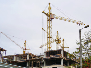 Fototapeta na wymiar Construction site. Four cranes and building. Concrete building under construction.