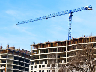 Big construction crane near building. Concrete building under construction. Building site.