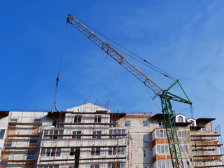 Industial crane and building against blue sky. Construction site.