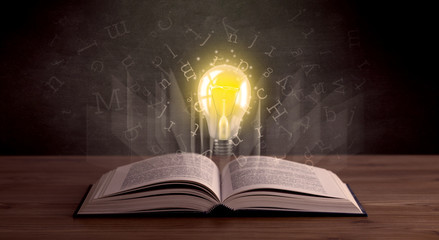 Shiny alphabet letters and yellow lightbulb hovering over open book 