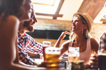 Happy friends having fun at bar - Young trendy people drinking beer and laughing together