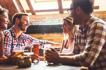 Happy friends having fun at bar - Young trendy people drinking beer and laughing together