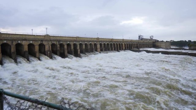 A view of a big reservoir with its flood gates open and massive quantity of water flowing through it.