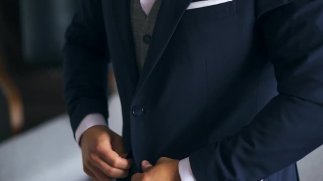 Stylish Caucasian Young Man In A Suit Buttoning Blue Jacket At A Wedding. Close Up