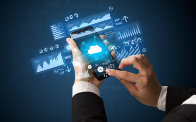 Female hand using smartphone with financial tracking concept illustrated by graphs and symbols
