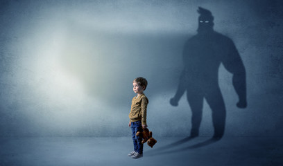 Cute kid in a room with plush on his hand and hero shadow on his background

