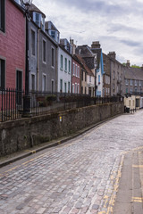 Queensferry, Scotland, UK - June 14, 2012: Quiet row of houses on Newhalls Road come in differnt color facades. Gray road surface and cloudscape.