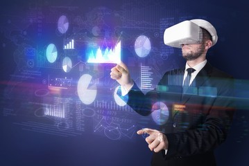 Elegant businessman in DJI goggles handling 3D reports and charts around him
