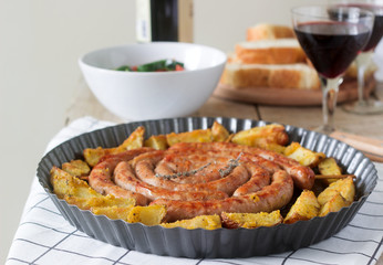 Aromatic meat sausages with potatoes, salad and wine on a wooden background. Selective focus.