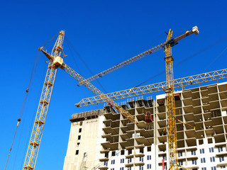 Two  tower cranes near building under construction. Construction site.