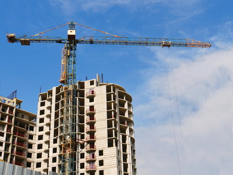Building and crane under construction against blue sky.