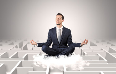 Young businessman meditate in yoga position on a cloud with infinity maze concept
