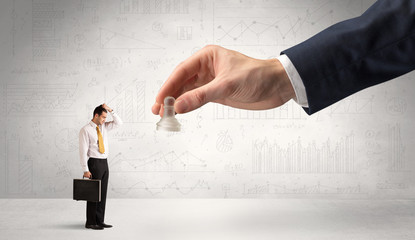 Little businessman is afraid to make the next step in his chess game with graphs, charts and...