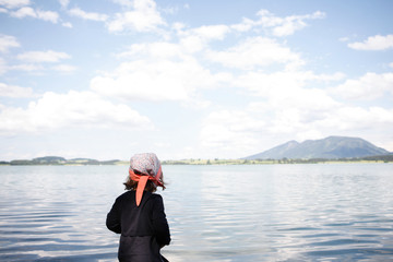 Mädchen am Ufer eines Sees vor Bergpanorama