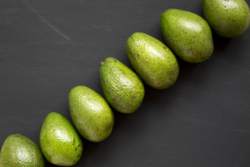 Whole avocados on black background, top view. Overhead, flat lay. Close-up.