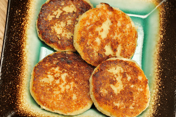 Healthy breakfast - freshly baked cottage cheese pancakes with sour cream on a plate - closeup