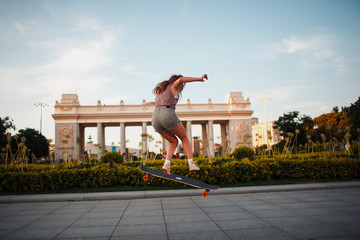 Young sporty woman riding on the longboard in the park