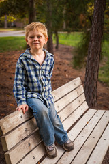 Young Boy Sitting on the Back of a Park Bench and Looking at the Camera