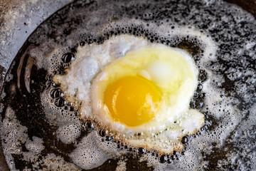 An egg frying in butter and oil in a carbon steel skillet