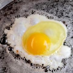 An egg frying in butter and oil in a carbon steel skillet