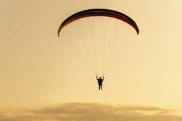 silhouette of paraplane on evening sky background, sunset time.