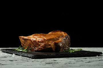Obraz premium Beef steak with rosemary on a black background with open space for text design or restaurant menus. Horizontal photo Black text area.