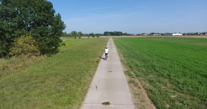 Luftaufnahme - Drohne folgt Radfahrer auf Radweg