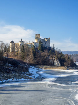 Medieval castle in Niedzica, Poland, in winter at partially frozen artificial Czorsztyn lake on Dunajec river. Sunset light.