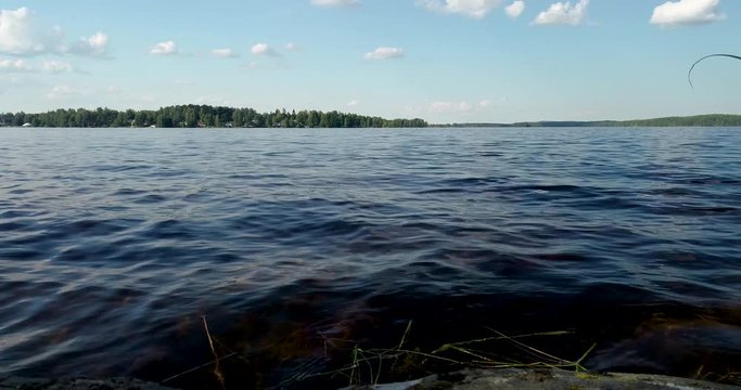 Waves by the lake seen from a cliff with forest on the other side of the lake on a summer day, Puumala Finland