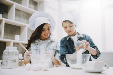 Portrait of Two Cute Children Cooking at Kitchen