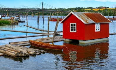 Fototapeta na wymiar Old wooden boat and red cottage on water