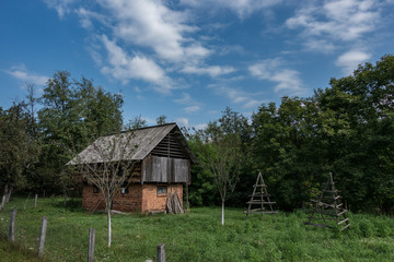 A barn on a green meadow with haystacks on a sunny day with blue sky and white clouds.