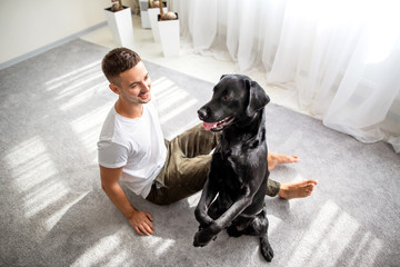 guy with his dog sitting at home playing