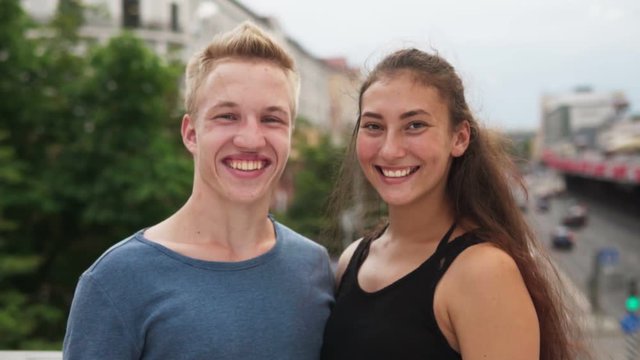 Multi-ethnic teenage couple having fun laughing at urban street on summer day