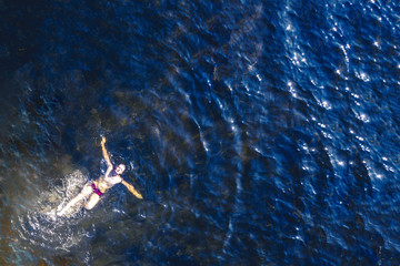top high aerial view of lonely person swim in the sea in a summer heaven lagoon beach